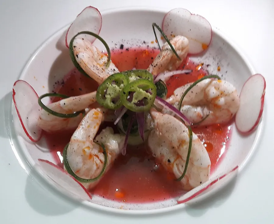 Aguachile de camarón con rodajas de pepino y cebolla morada en salsa roja