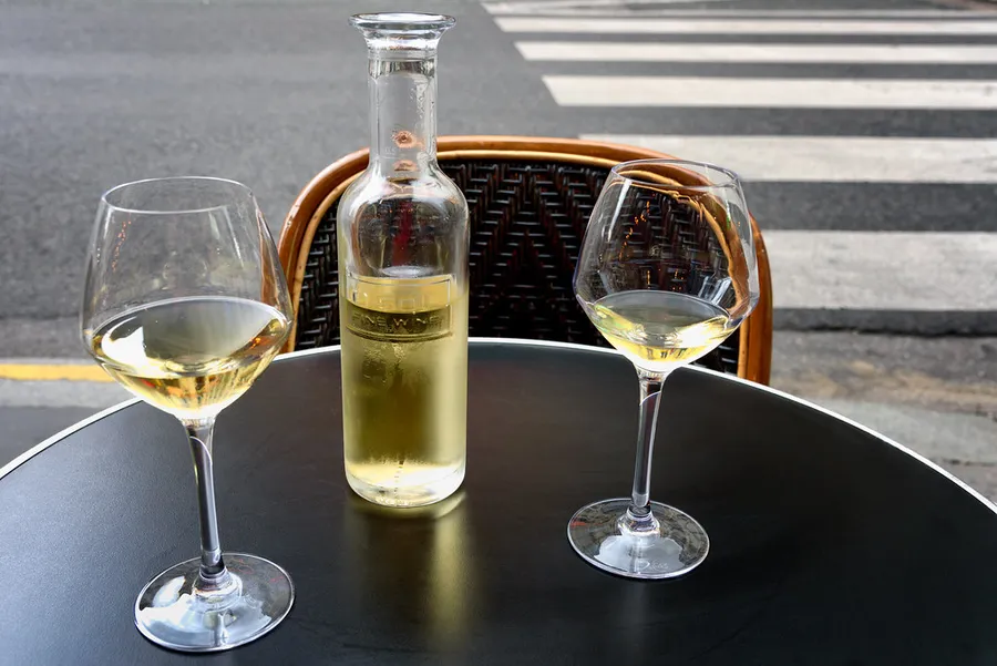 Dos copas de vino blanco y una botella en una mesa