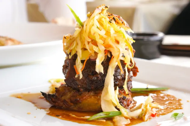 Corte de carne emplatado con verduras en tiras y salsa
